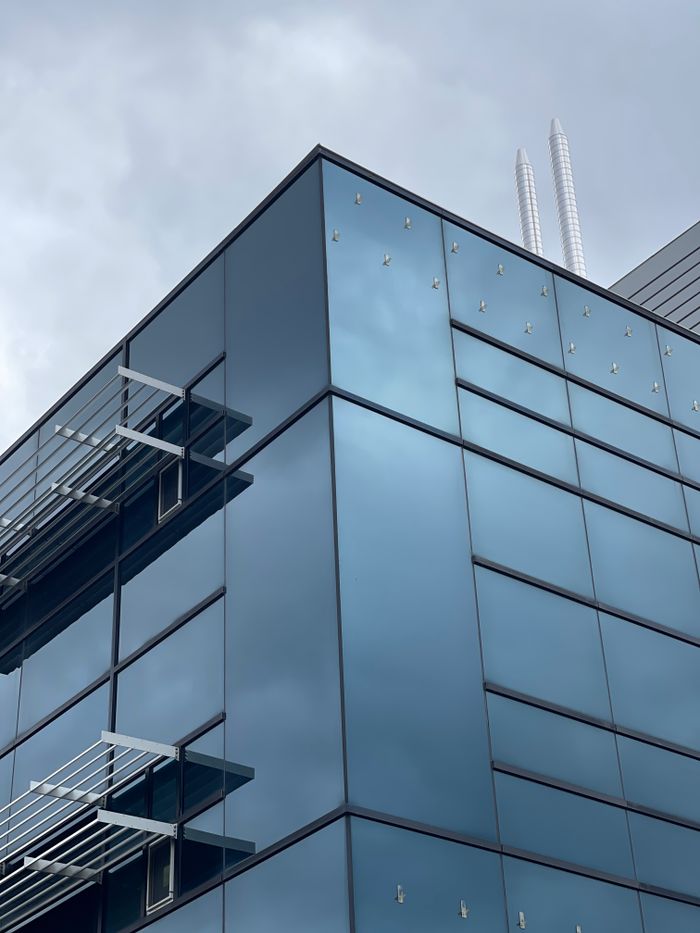 Sleek modern building in Guelph, Ontario, showcasing a reflective glass facade against a cloudy sky.